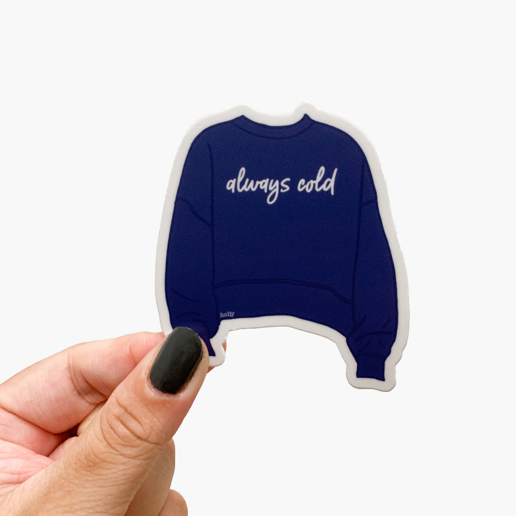 A sticker featuring a cozy blue sweater and text that reads, Always cold.