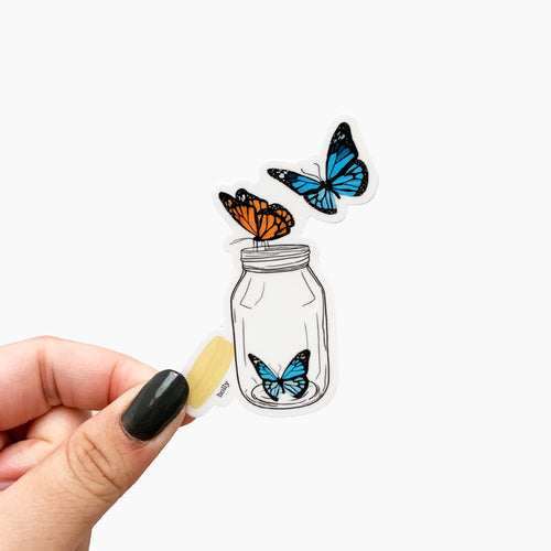 A sticker featuring orange and blue butterflies flying out of a mason jar.