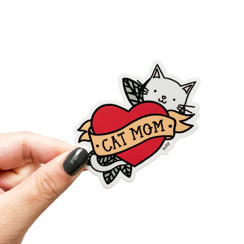 A funny sticker with a play on the popular mom tattoo with the heart and arrow through it, but has a cat and leaves instead with text that reads, Cat Mom.