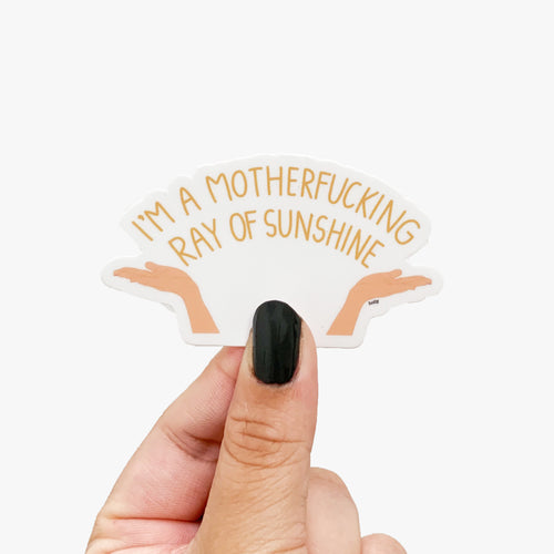 A funny sticker of two open hands facing upwards with text in between them that reads, I’m a motherfucking ray of sunshine.