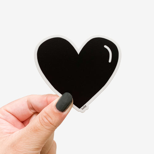 A sticker featuring a matte black heart with a small white line detail.